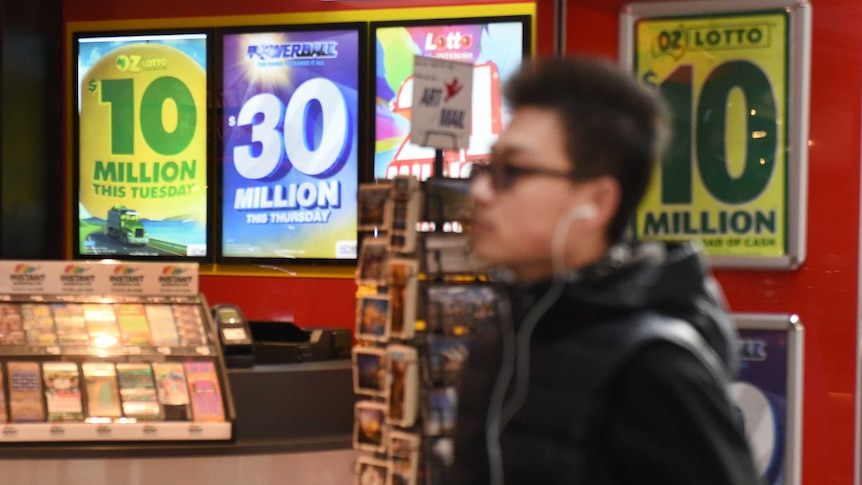 A man walks past a newsagent advertising lotto