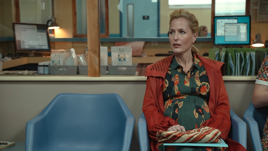 Jean Milburn (Gillian Anderson) from Sex Education sits in a doctor's waiting room, heavily pregnant.