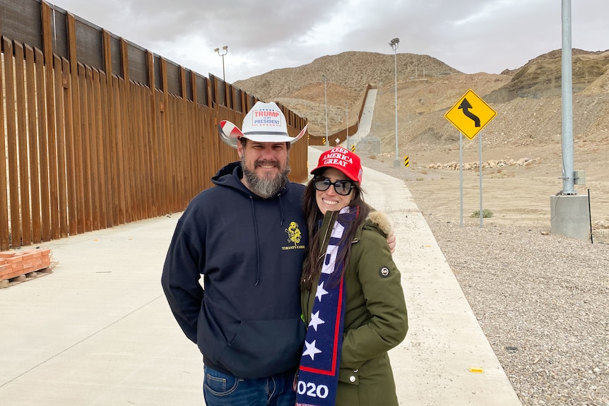 A man wearing a Trump hat with his arms around a woman wearing a Trump cap and scarf