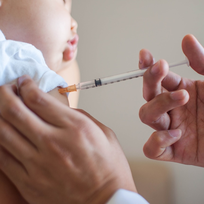 A doctor is injecting a vaccine to a baby boy
