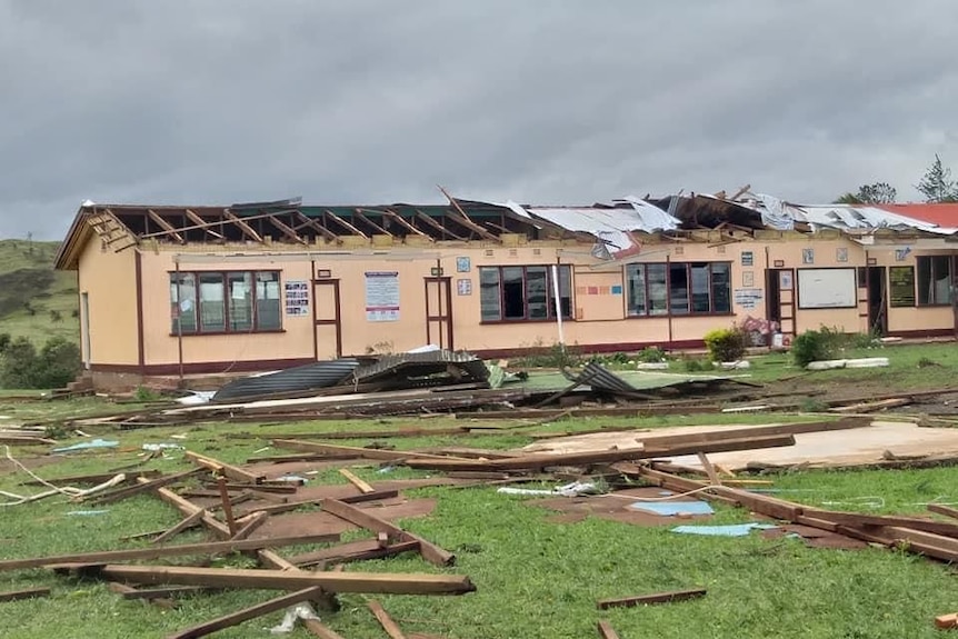 The roof of a building with shattered windows lay in pieces on the ground.