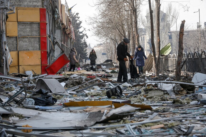 Residents walk near a building destroyed in the course of the Ukraine-Russia conflict