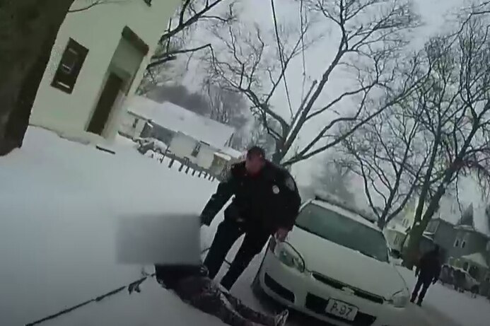 Image shows girl lying in snow with police officer standing over her