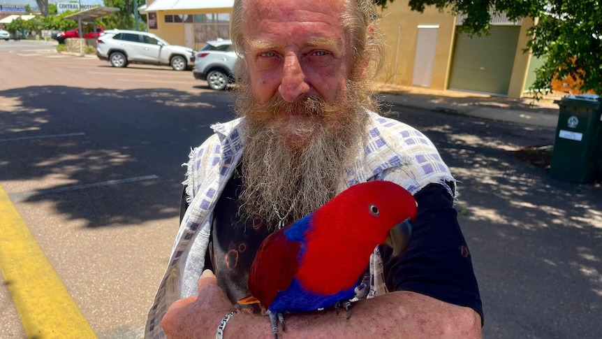 Man standing with red parrot on arm
