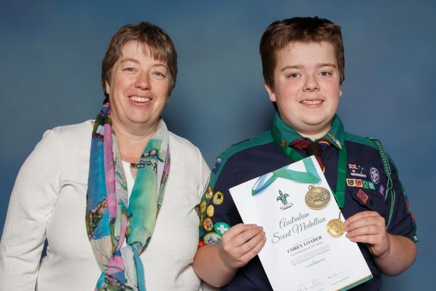 A young man in his Scouts uniform with his mother