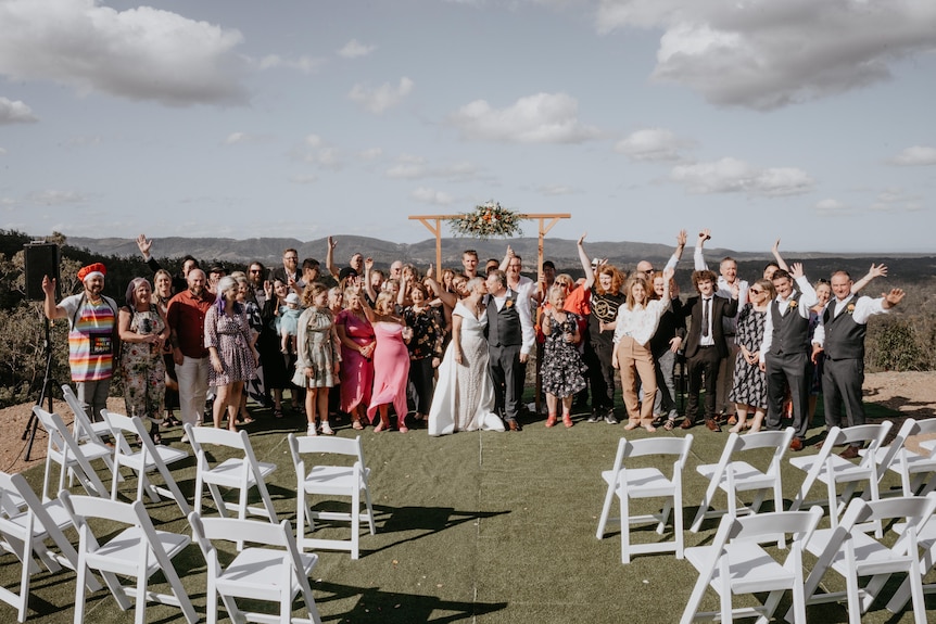 A large group of happy people at an outdoor wedding.