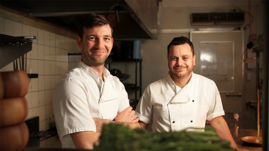Tom Chiumento and Simon Evans stand in chef whites in their kitchen.