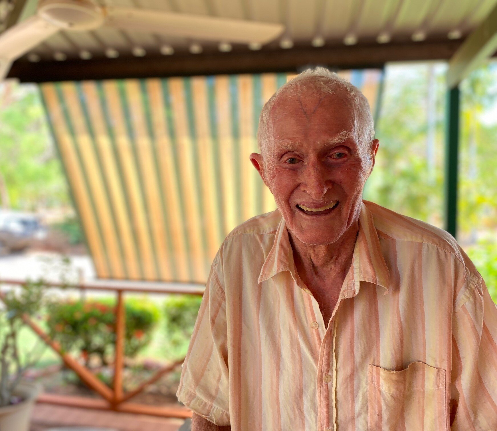 An elderly man smiles widely