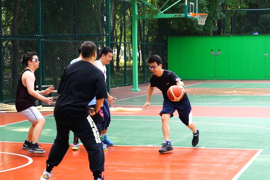 A group of people playing basketball in China.