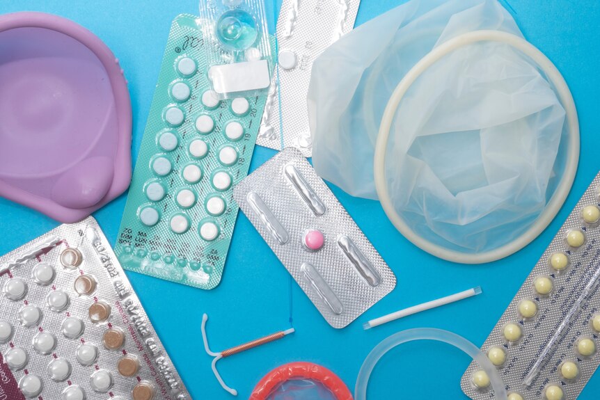 An array of contraceptive devices displayed in front of a blue background from condoms to the pill.