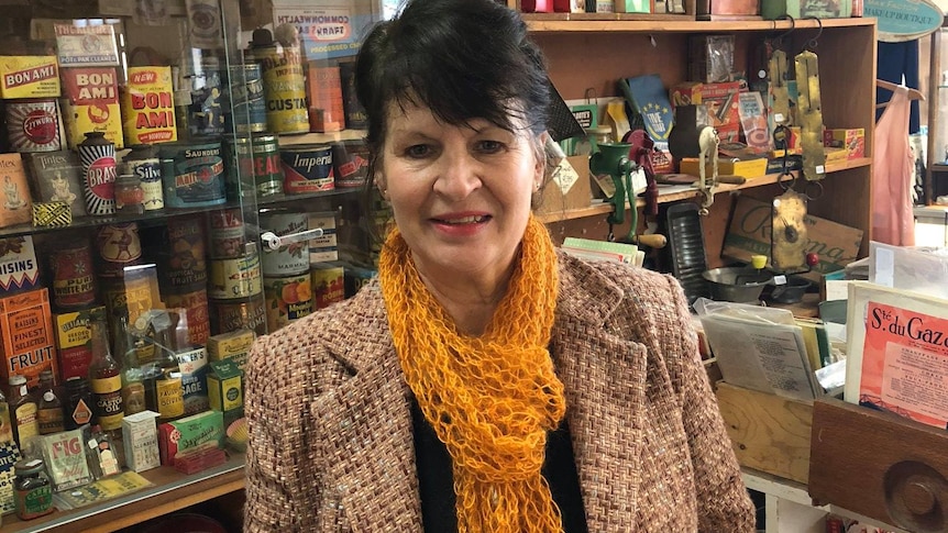 A shop owner standing in her shop infront of old tins and collectables 