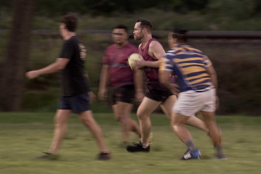 A man runs with a football between other players