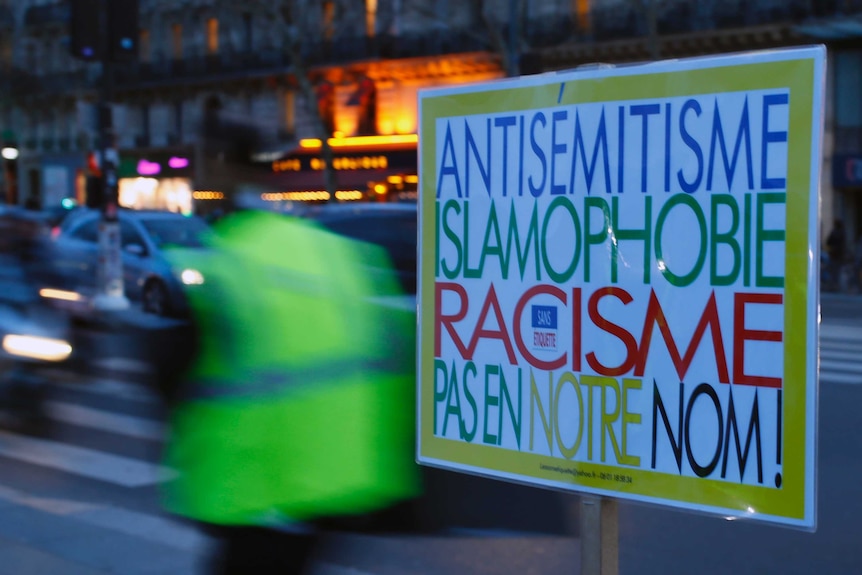 A poster reading "Anti-Semitism, Islamophobia, Racism, Not in Our Name" in French.