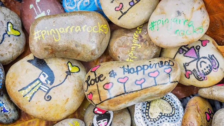 A collection of rocks painted with bright colours and positive messages.