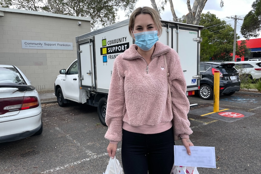 Rachel is a single mum from Frankston, pictured holding two grocery bags collected from charity Community Support Frankston