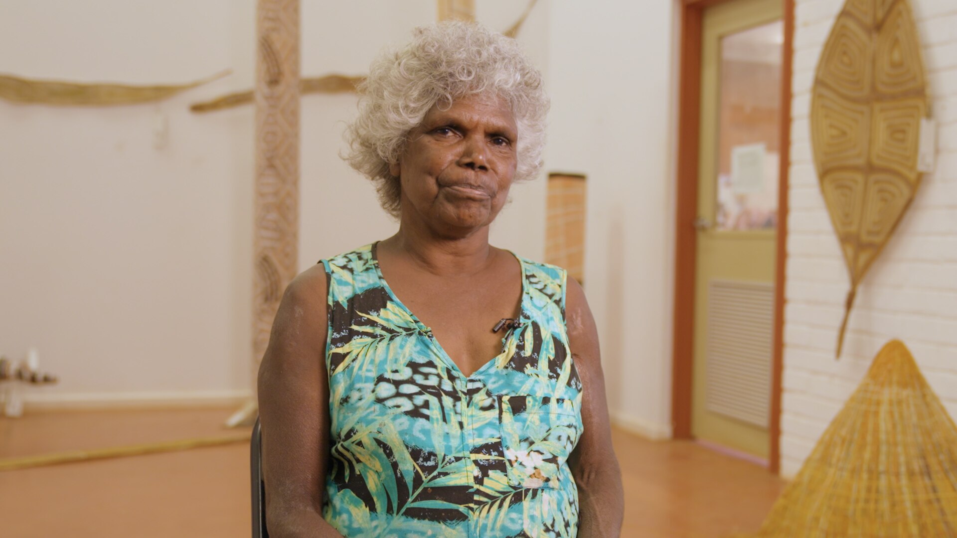 Freda Wayartja Ali, a Burarra woman in her 60s with short curly grey hair, wearing a pale blue singlet in a gallery.