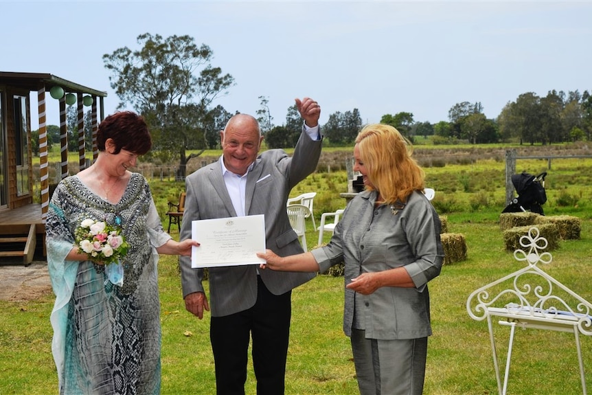 Couple Margie and Dave look at their marriage certificate on their wedding day.