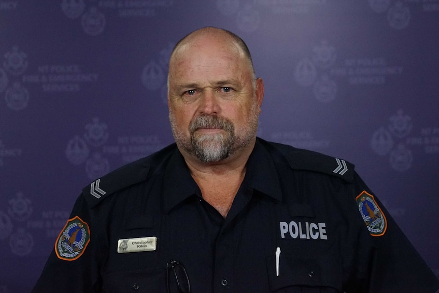 A man stands in front of the camera, tears in his eyes and wearing an NT Police uniform.