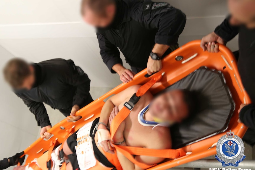 Paramedics carry a man on a stretcher.