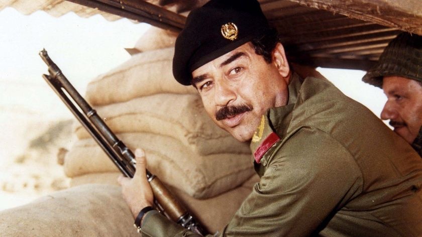 Former Iraqi President Saddam Hussein poses with a gun