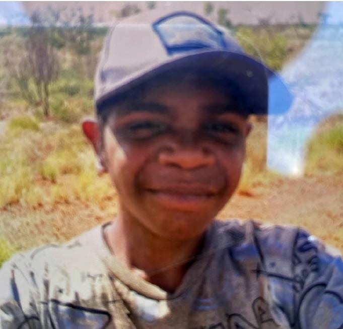 A boy with a hat on, smiling at the camera