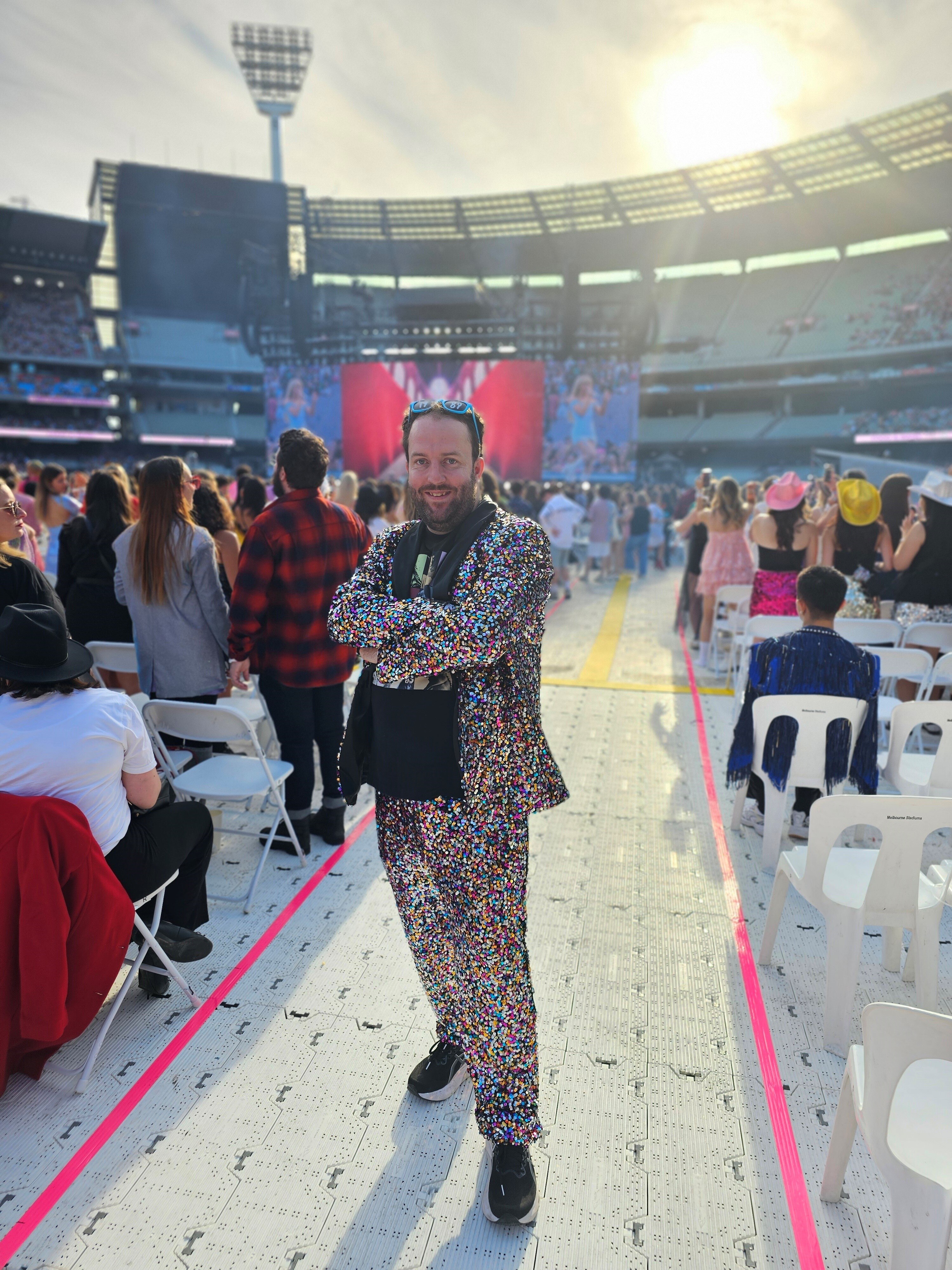 Man in sparkly suit stands between stadium seats