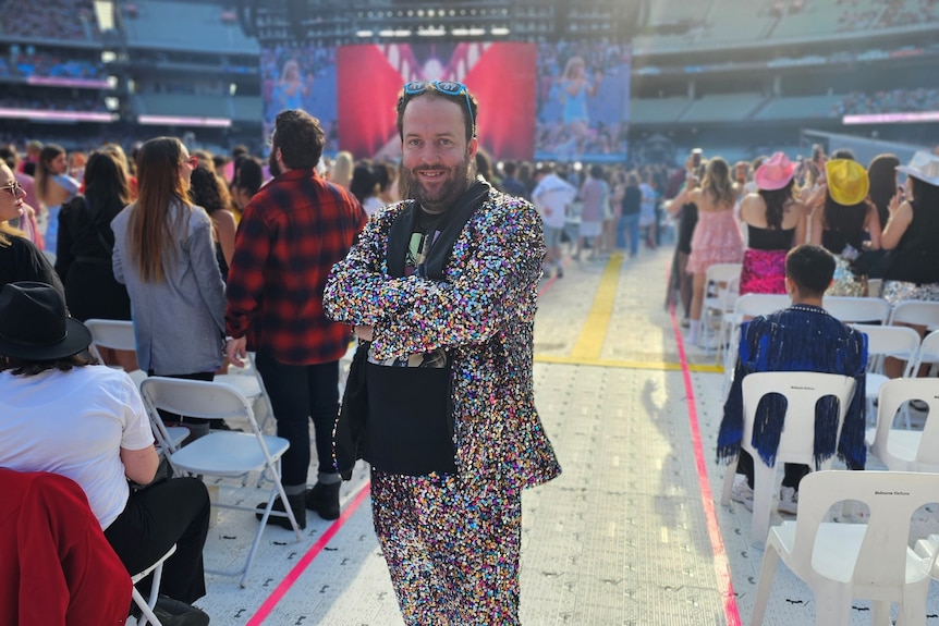 Man in sparkly suit stands between stadium seats