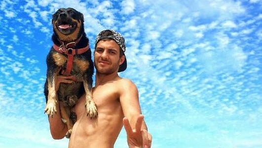 Jacob Pagano and his dog pose for a photograph underneath a blue sky on one of far north Queensland's beaches.
