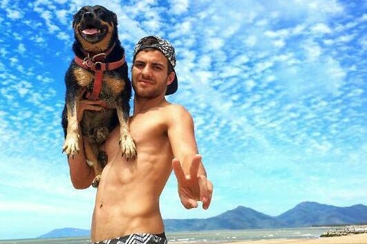 Jacob Pagano and his dog, Sacchi, pose for a photograph underneath a blue sky on one of far north Queensland's beaches.