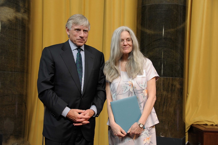 Olds stands next to Lee C. Bollinger, grasping a blue folder - her Pulitzer.