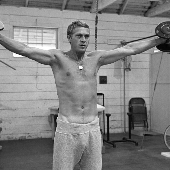 Actor Steve McQueen lifts weights in a gym