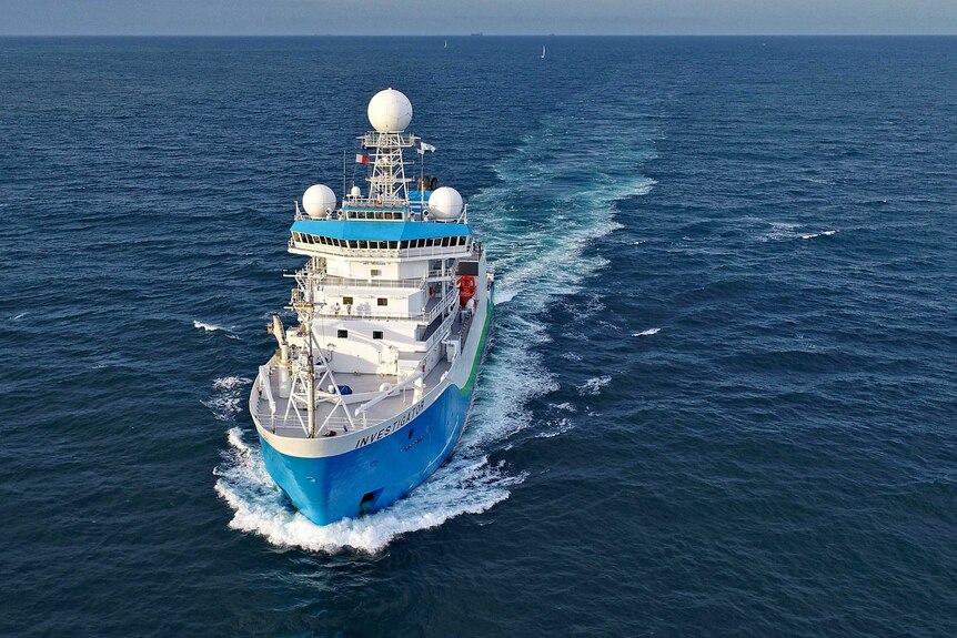 CSIRO research vessel Investigator makes its way through the open sea. Two other vessels are barely visible on the horizon.