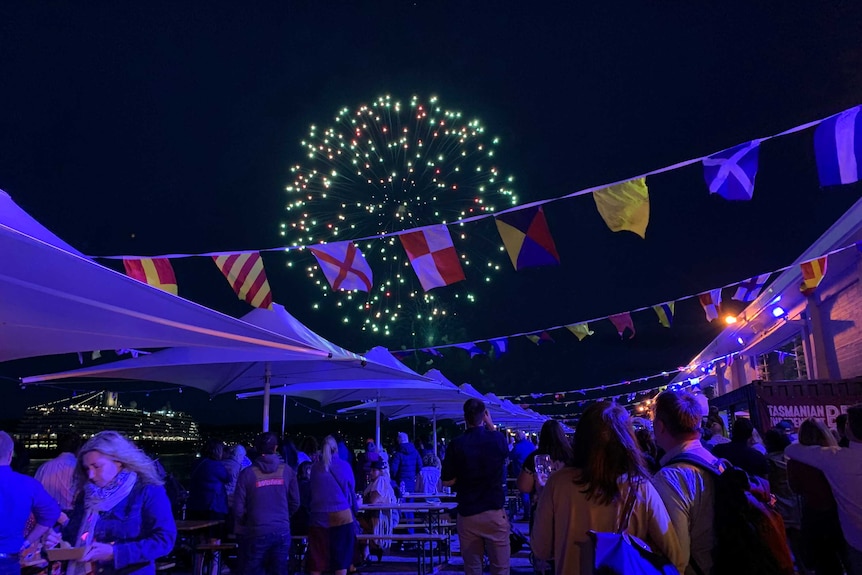 Fireworks are seen in the sky at night time above a group of people