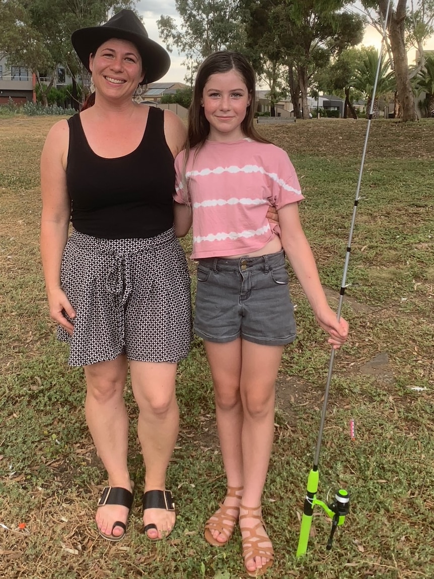 A girl and her mother holding a fishing rod