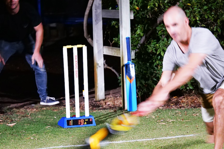 A man moves to hit a cricket ball