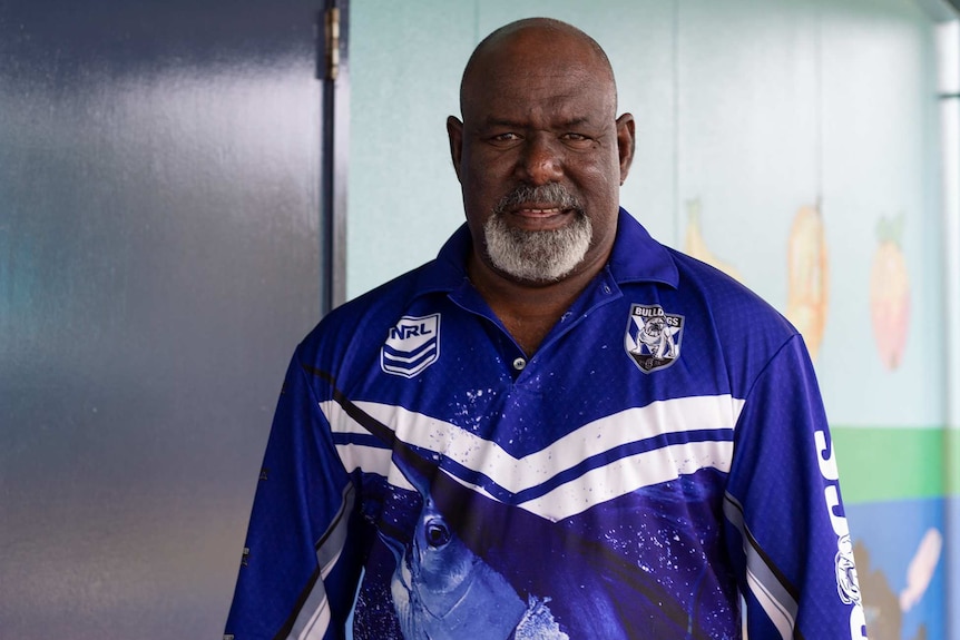 A man in an NRL shirt smiles to camera.