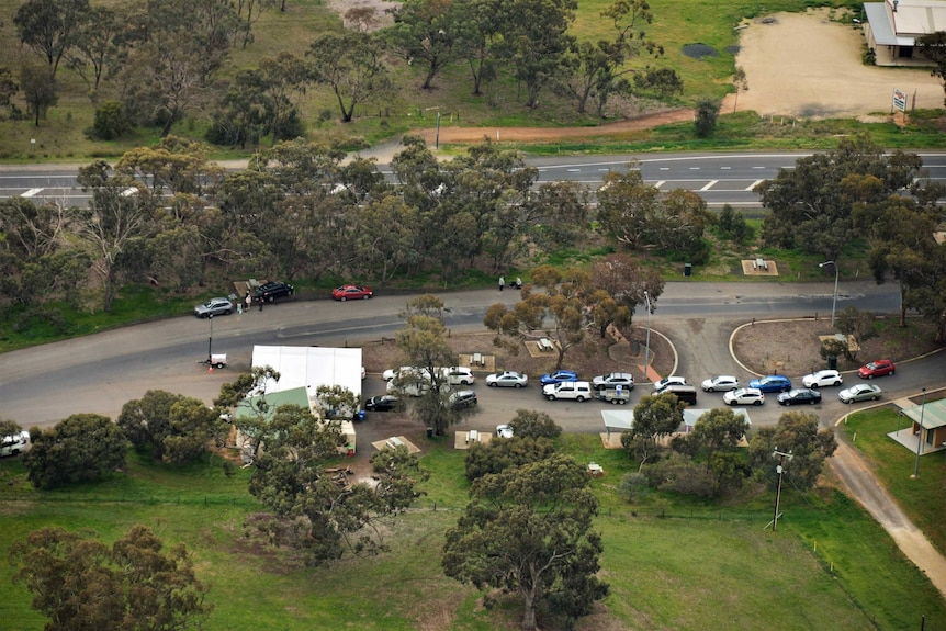A queue of cars on a side road with trees photographed from the air