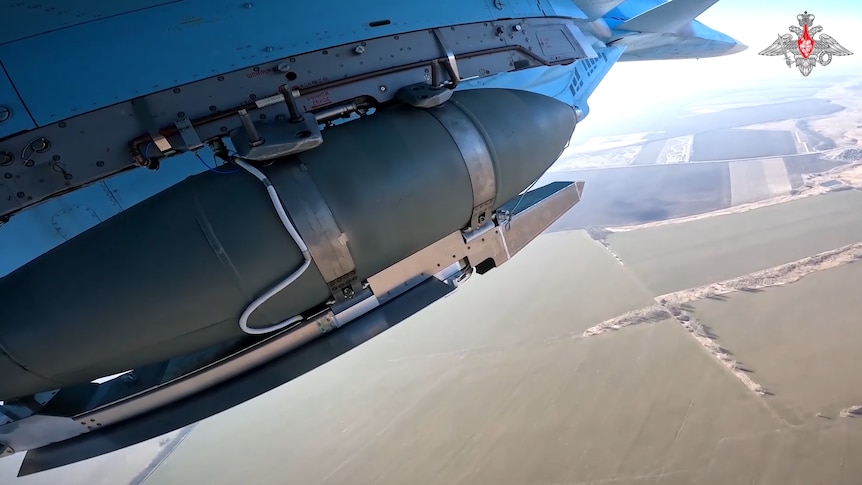 Close-up of a bomb being carried under a fighter jet taking off. 