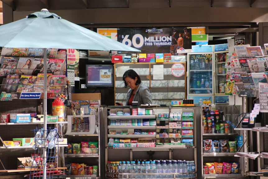 Woman stands behind counter at news stand