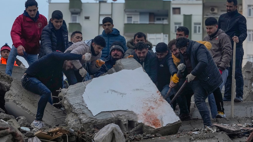 Men search for people among the debris in a destroyed building.