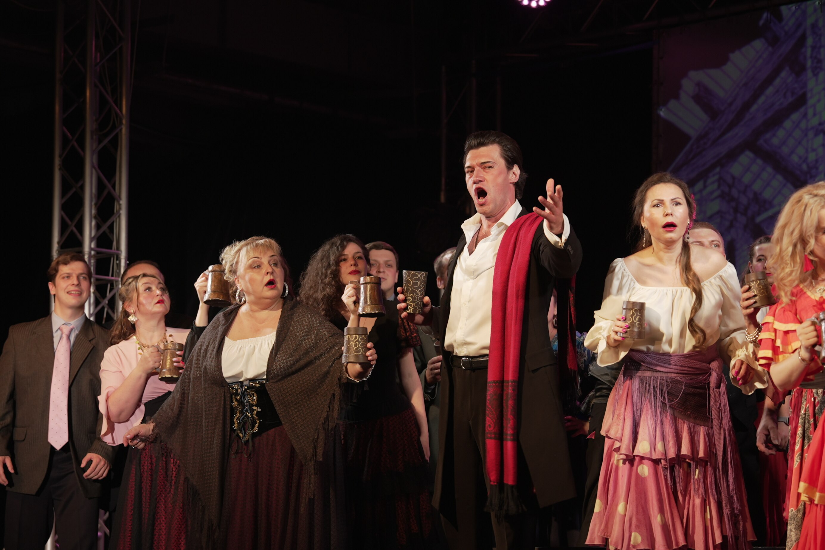 Performers on a stage. a man with an open mouth singing in the middle