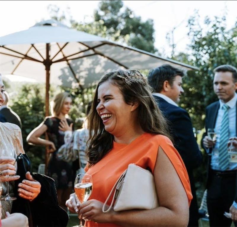 Fiona holds a glass of wine in her hand and is laughin