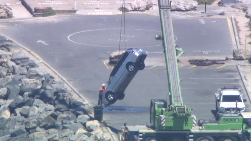 A car is removed from the water via crane at South Mole.