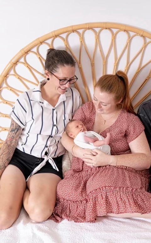 Two mothers holding newborn baby