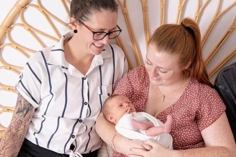 Two mothers holding newborn baby