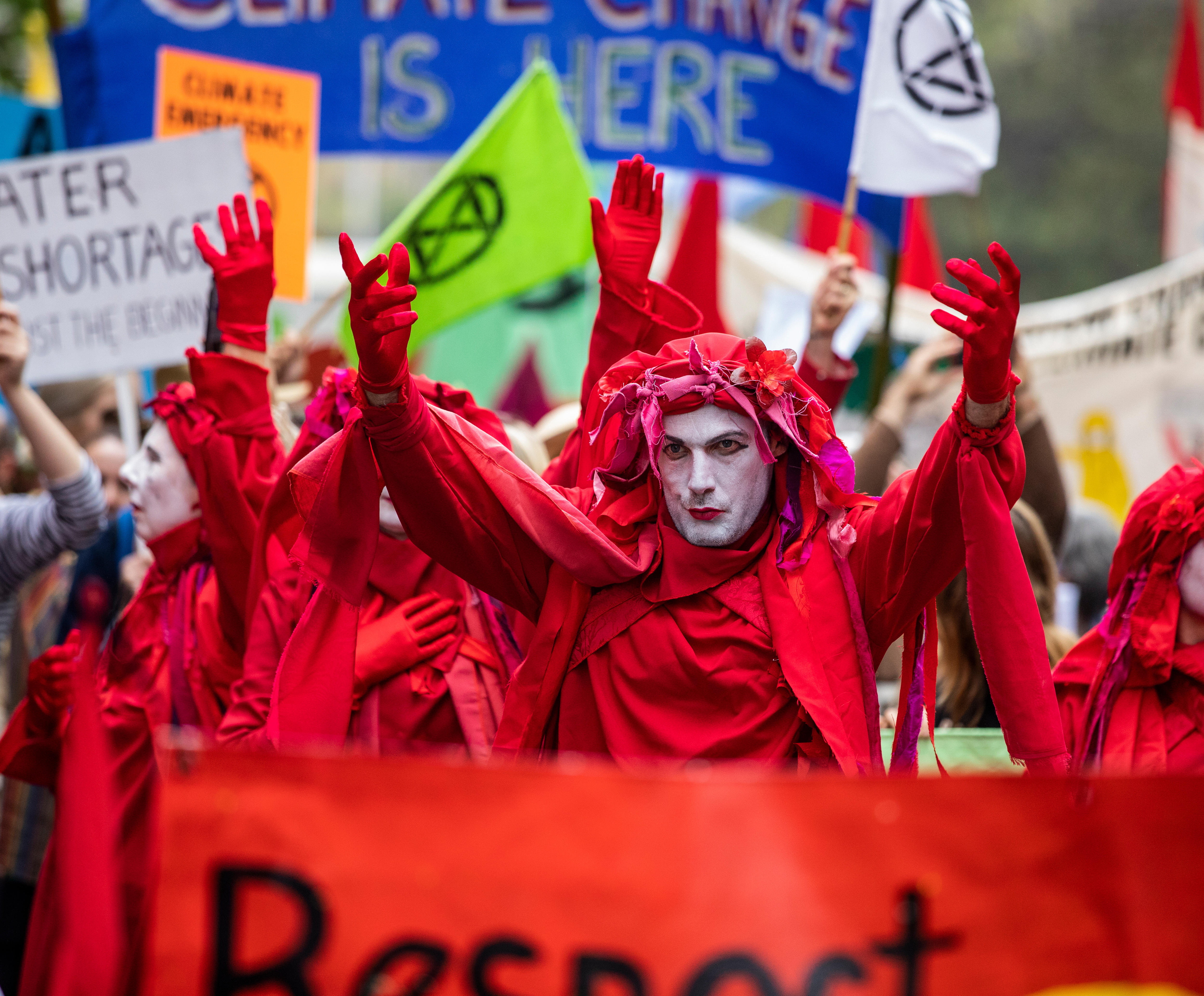 People with red capes chant in the street