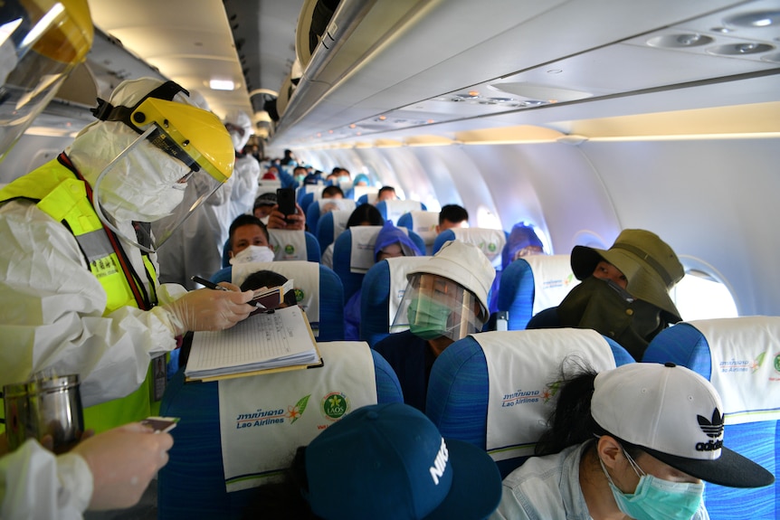 A Chinese customs officer in protective suit inspects documents of passengers on a plane