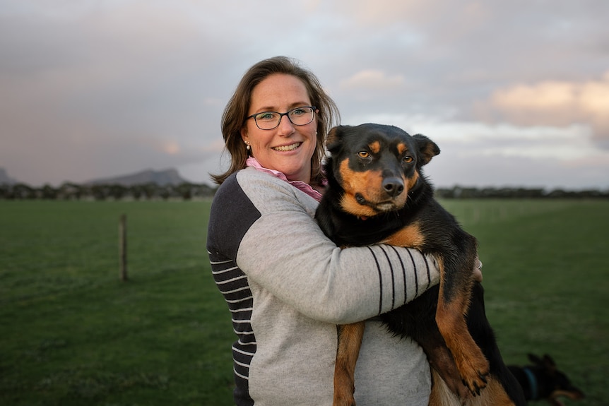 woman squatting in red dirt parting a working dog