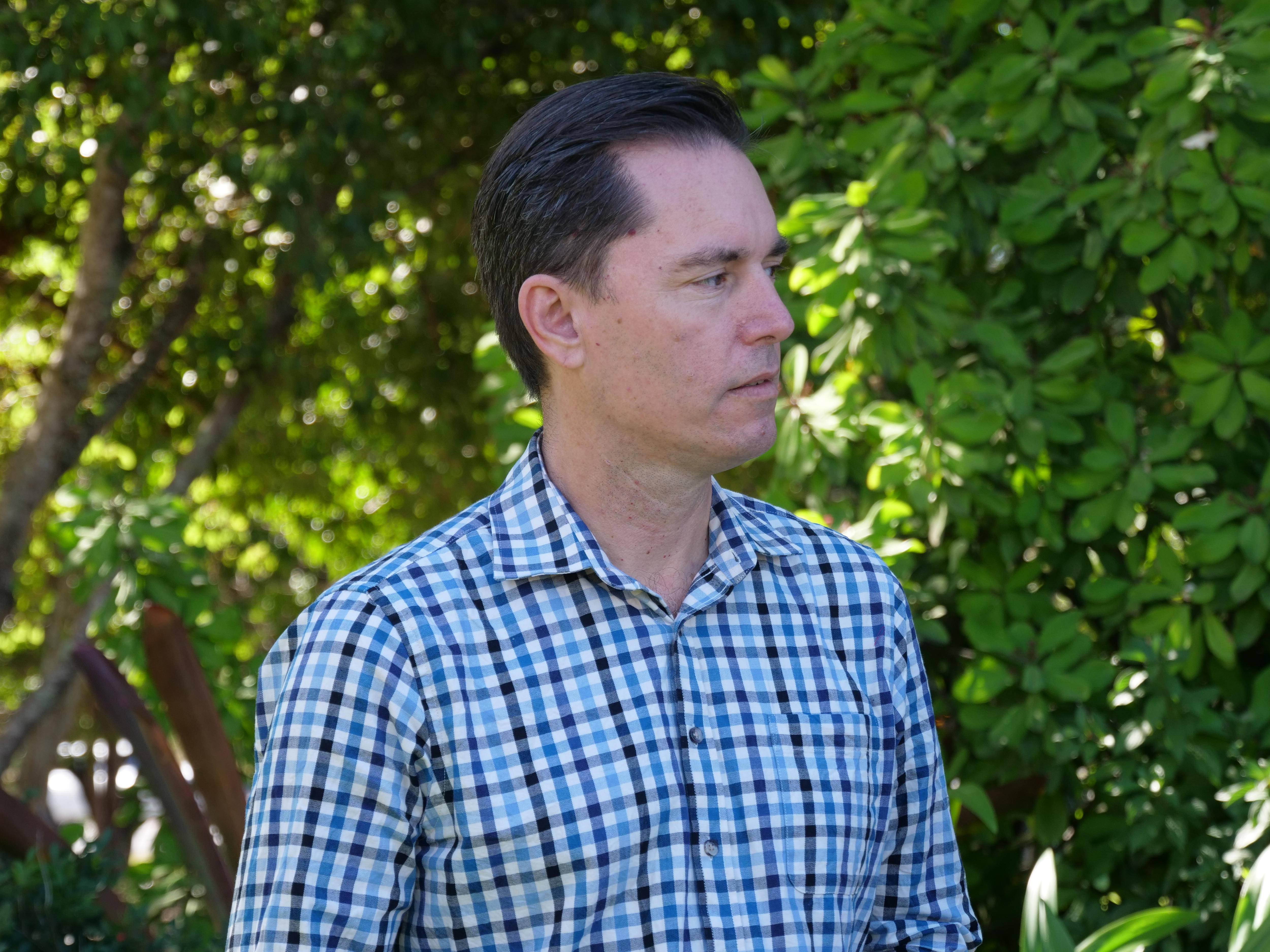 A man stares intently at a second person as they speak about a serious topic.