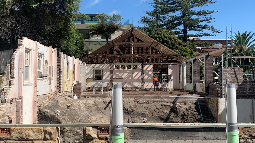 A house under restoration. The image looks down the length of the house with only the walls and the end roof still in tact